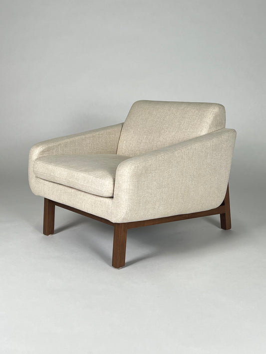 Light tan fabric chair with walnut frame and back legs.