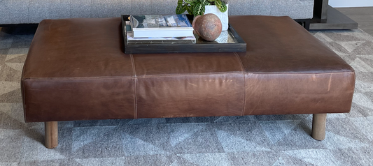 Brown leather coffee table or bench with round nude wood legs