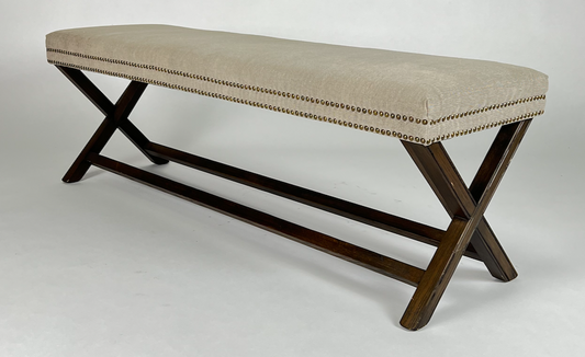X-base bench with neutral weathered upholstery with nailhead trim