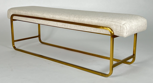 Bench with cream upholstered seat atop a brass sled frame