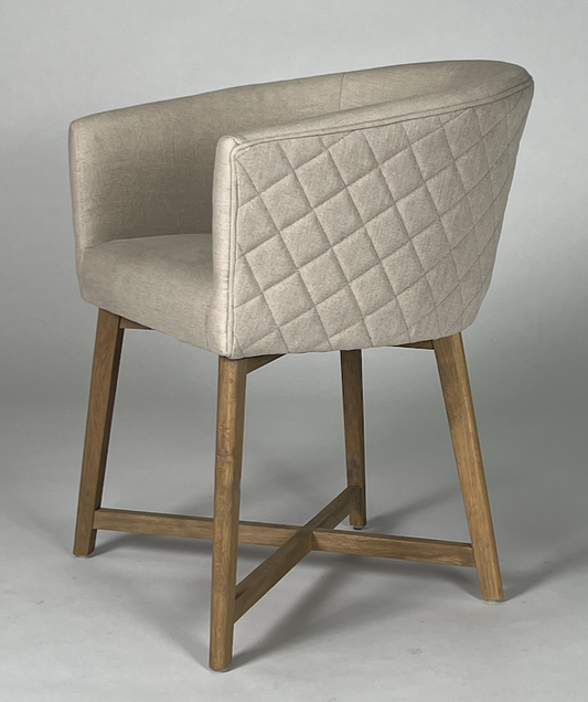 Light tan upholstered chair with rounded quilted back, wood frame