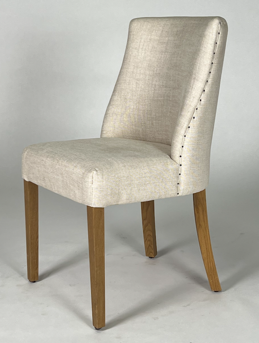 Cream upholstered barrel back dining chair with nailhead trim, brown legs