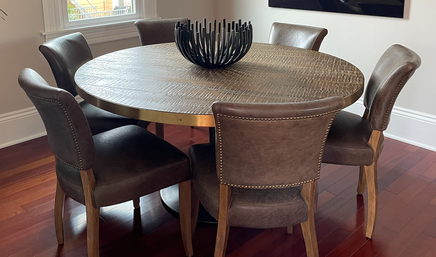 Round dining table, burnt oak top with brass band, black pedestal base