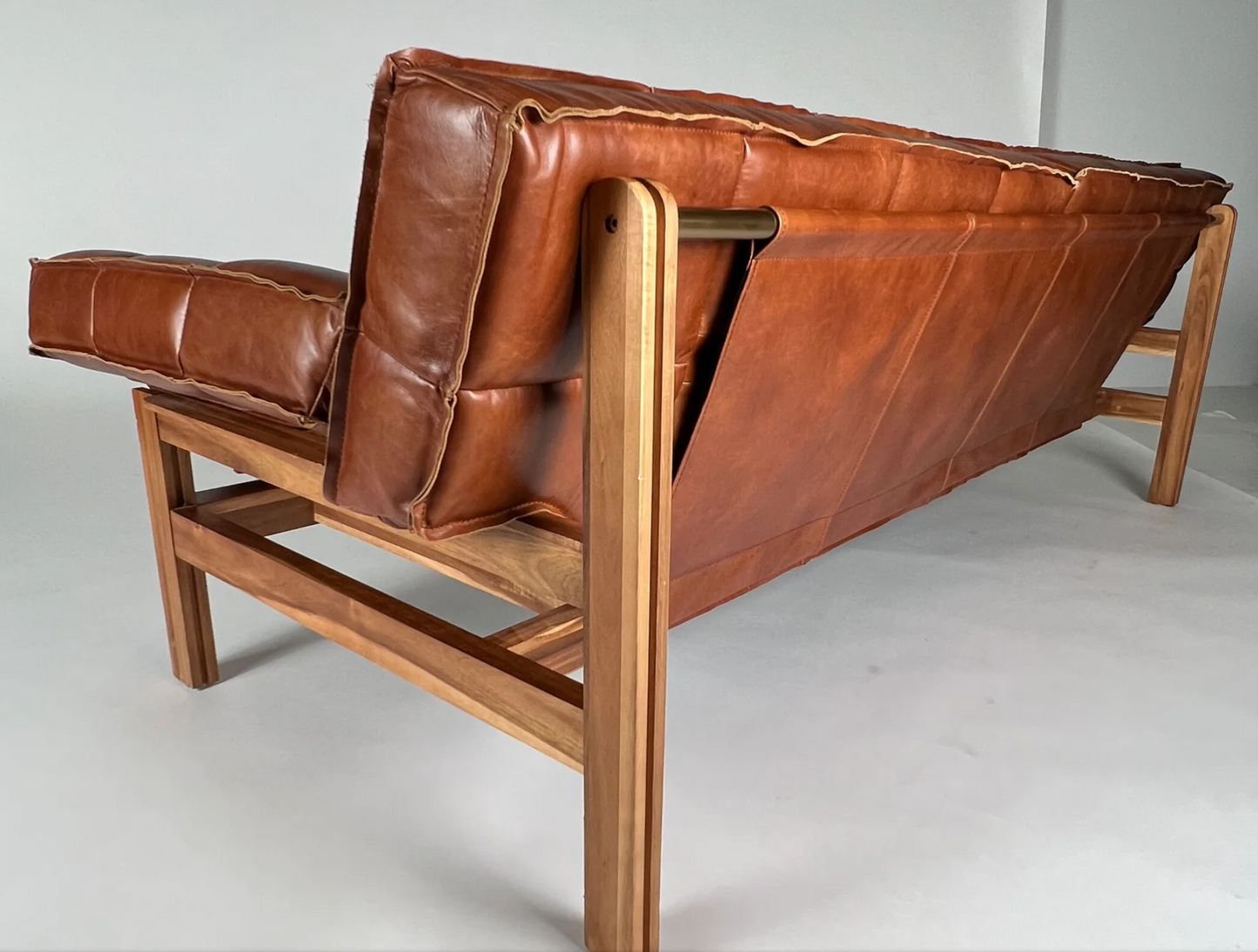 Brown leather channeled sofa, sling back, brown wood frame. 